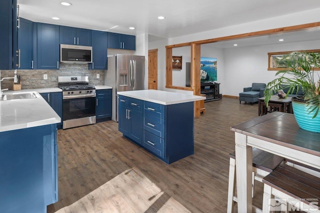 kitchen featuring light countertops, appliances with stainless steel finishes, blue cabinetry, and a sink