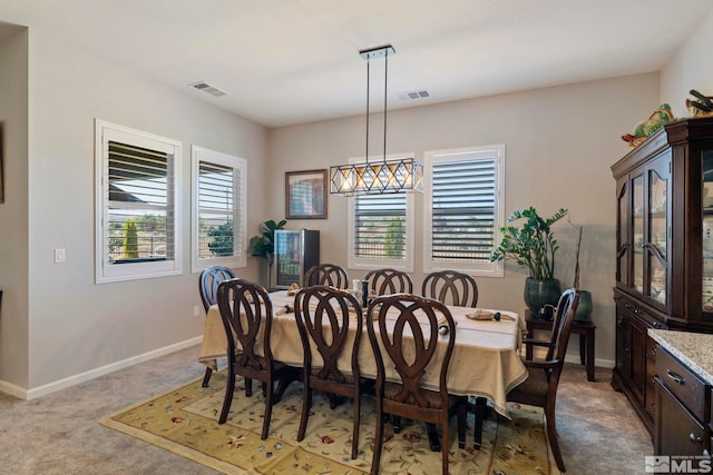 dining space featuring light colored carpet, visible vents, and baseboards