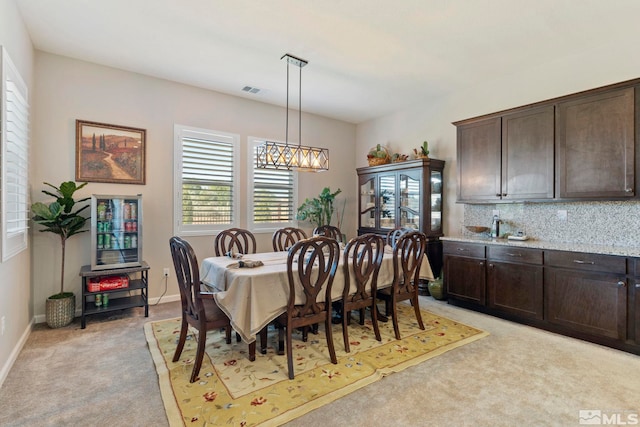 dining space with light carpet, a chandelier, visible vents, and baseboards