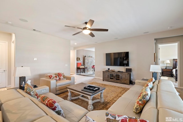 living area featuring light colored carpet, visible vents, ceiling fan, and baseboards