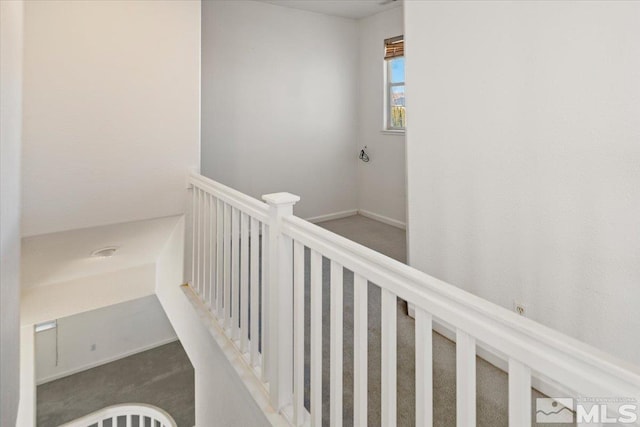 hallway with carpet, an upstairs landing, and baseboards