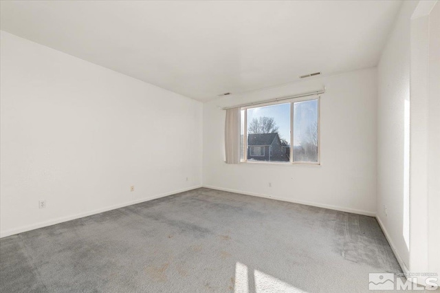 unfurnished room featuring baseboards, visible vents, and carpet flooring