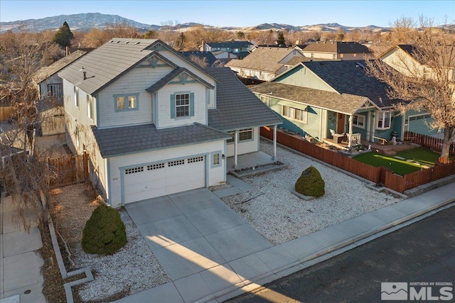 view of front facade featuring driveway, a garage, a residential view, fence, and a mountain view