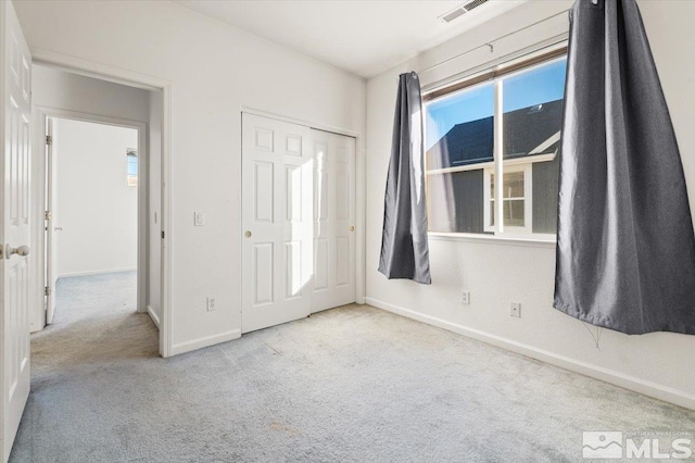 unfurnished bedroom with light carpet, baseboards, visible vents, and a closet