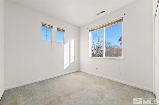 spare room with light carpet, a healthy amount of sunlight, baseboards, and visible vents