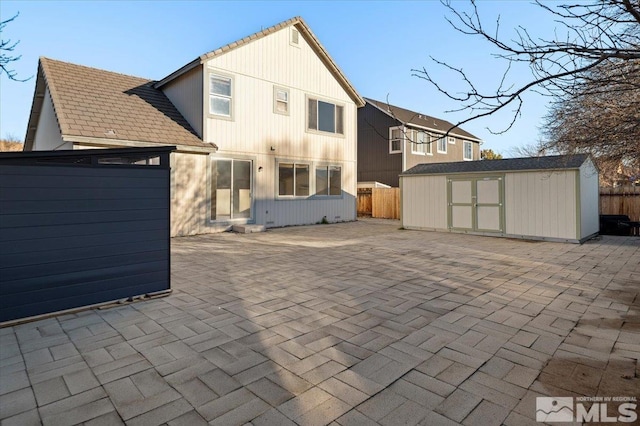 rear view of house featuring a storage shed, a patio, an outdoor structure, and fence