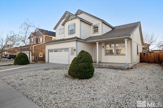 traditional-style home with a garage, driveway, and fence