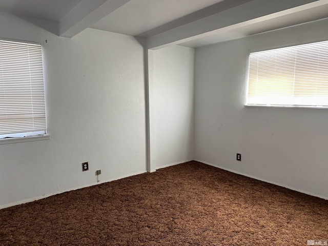 carpeted empty room with beam ceiling