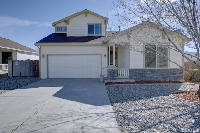 view of front of property featuring a garage, concrete driveway, stone siding, and fence