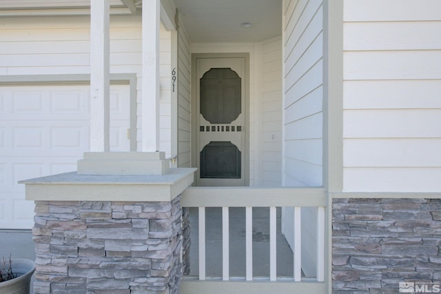 view of exterior entry with a garage and stone siding