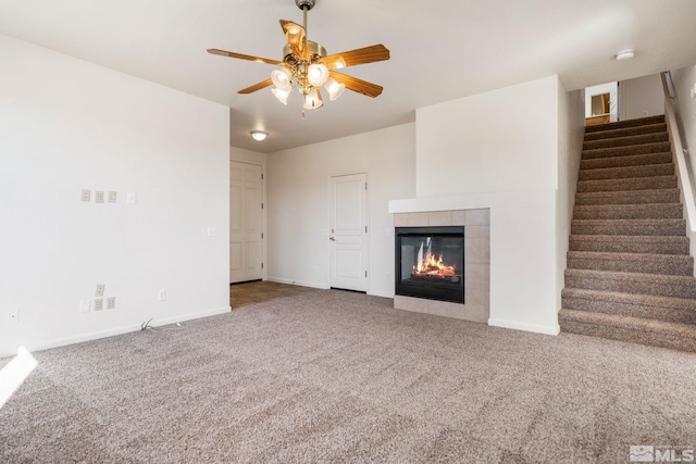 unfurnished living room with baseboards, stairway, carpet flooring, and a tile fireplace