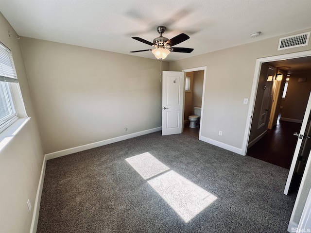 unfurnished bedroom with baseboards, visible vents, dark carpet, and a ceiling fan