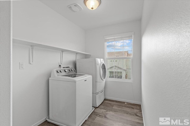 laundry room featuring laundry area, light wood finished floors, washing machine and dryer, and baseboards