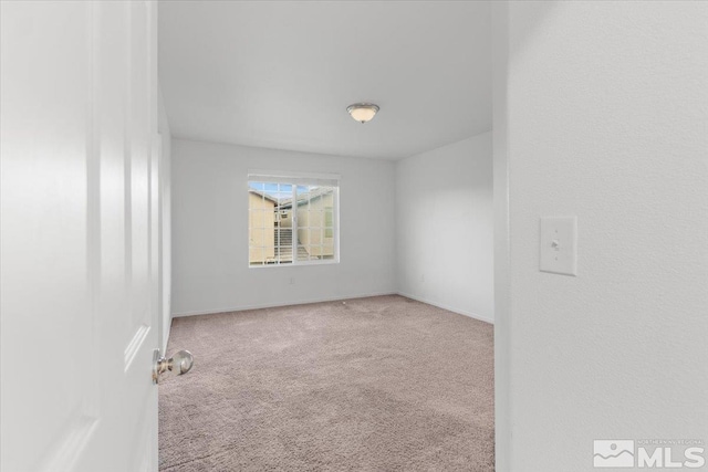 carpeted spare room featuring baseboards