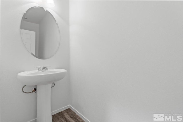 bathroom with a sink, baseboards, and wood finished floors