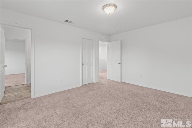 spare room featuring light carpet, visible vents, and baseboards