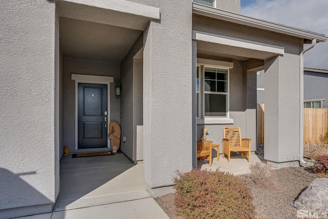 doorway to property with fence and stucco siding