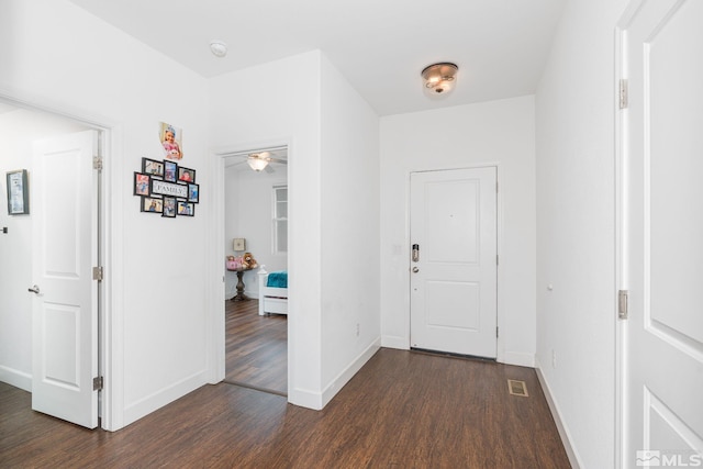 foyer entrance featuring dark wood-type flooring, visible vents, and baseboards