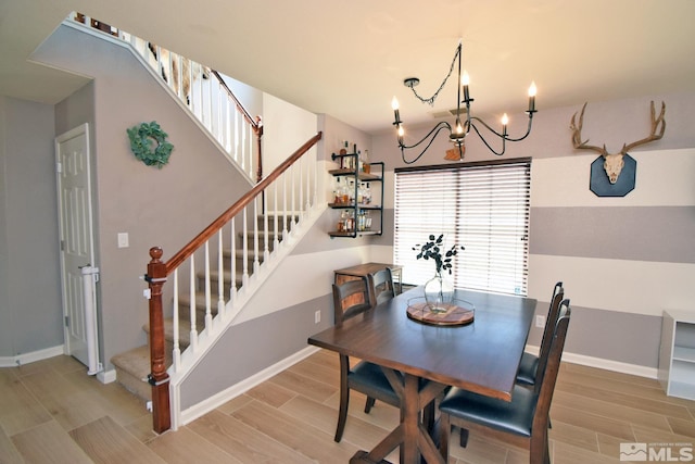 dining space featuring wood finish floors, an inviting chandelier, baseboards, and stairs