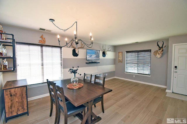 dining room with a chandelier, baseboards, visible vents, and wood tiled floor