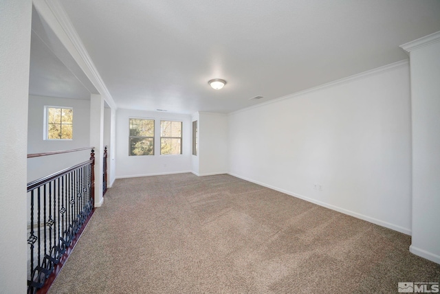 carpeted spare room featuring crown molding and baseboards