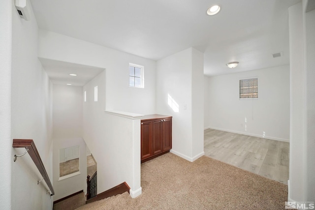 interior space featuring visible vents, light colored carpet, an upstairs landing, and baseboards