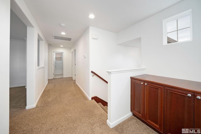 hall featuring light carpet, an upstairs landing, visible vents, and baseboards