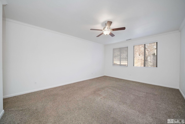 carpeted spare room with a ceiling fan, visible vents, crown molding, and baseboards