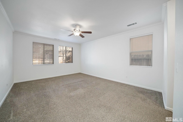 carpeted spare room with a ceiling fan, baseboards, visible vents, and crown molding