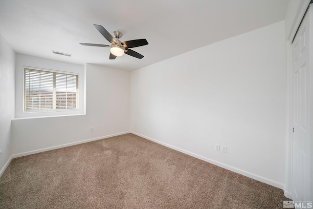 carpeted empty room with visible vents, ceiling fan, and baseboards