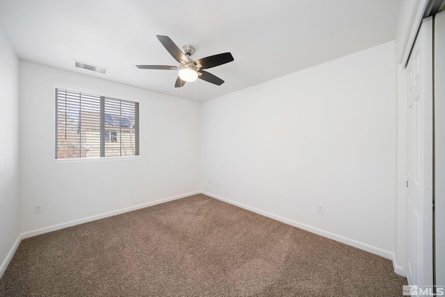 carpeted empty room featuring a ceiling fan, visible vents, and baseboards