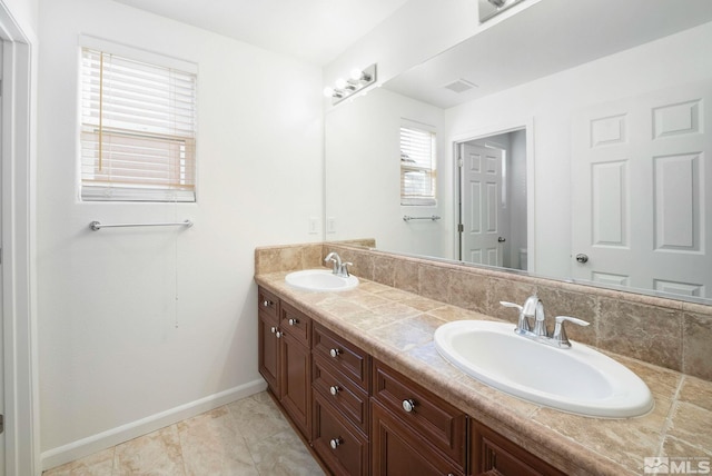 bathroom with visible vents, a sink, baseboards, and double vanity