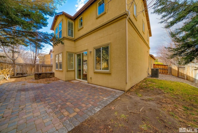 back of property with central AC, a patio area, a fenced backyard, and stucco siding