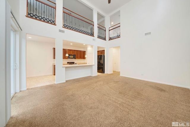 unfurnished living room with baseboards, visible vents, and light colored carpet