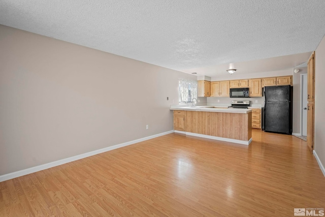 kitchen featuring light wood-style floors, a peninsula, light countertops, black appliances, and light brown cabinets