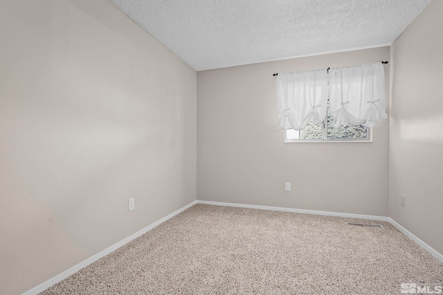 empty room with carpet floors, visible vents, baseboards, and a textured ceiling