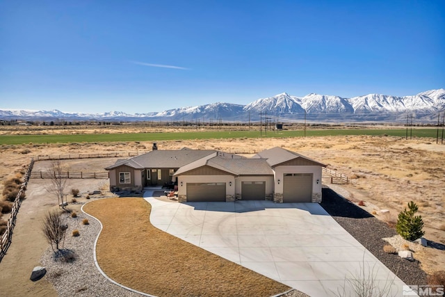 view of front of house with a mountain view, a garage, fence, concrete driveway, and stone siding