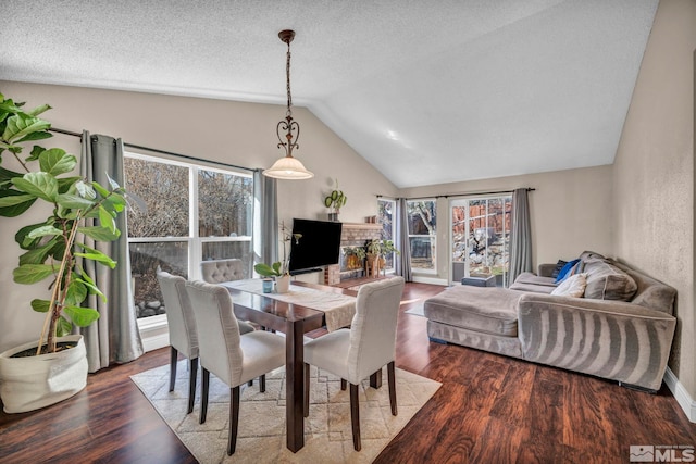 dining room featuring lofted ceiling, a textured ceiling, wood finished floors, and a healthy amount of sunlight