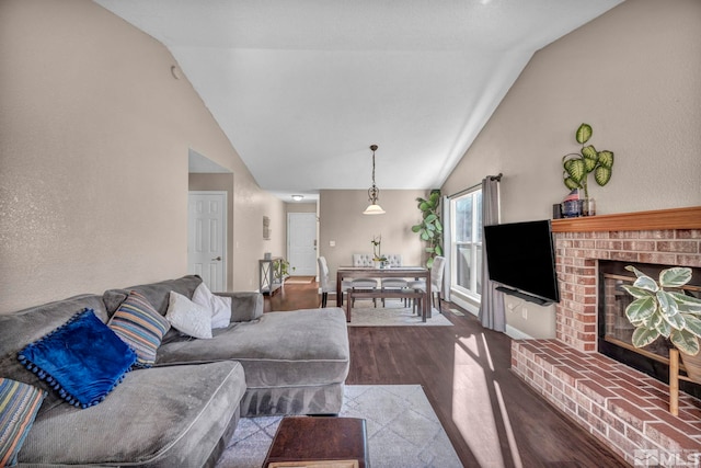 living area with high vaulted ceiling, a fireplace, and wood finished floors