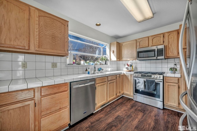 kitchen featuring dark wood finished floors, tile countertops, tasteful backsplash, appliances with stainless steel finishes, and light brown cabinets