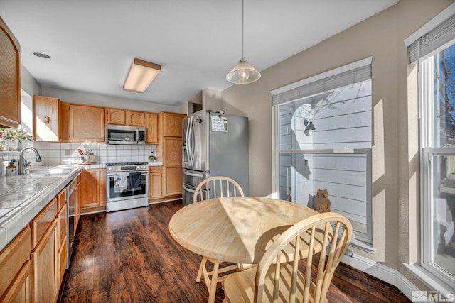 kitchen featuring tile countertops, stainless steel appliances, dark wood-style flooring, a sink, and tasteful backsplash