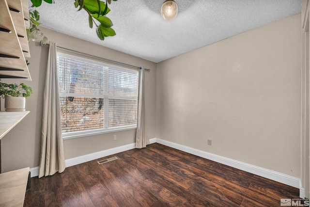 spare room featuring baseboards, a textured ceiling, visible vents, and dark wood-style flooring