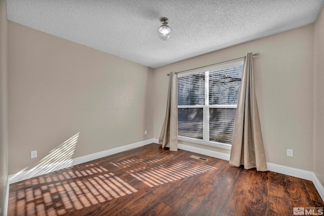 unfurnished room featuring a textured ceiling, wood finished floors, and baseboards