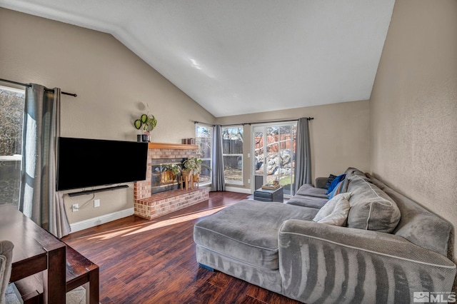 living room featuring baseboards, a textured wall, lofted ceiling, wood finished floors, and a brick fireplace