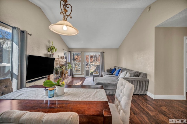 living area with lofted ceiling, a textured wall, baseboards, and wood finished floors