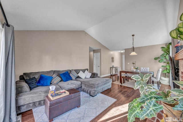 living area featuring lofted ceiling, a brick fireplace, and wood finished floors