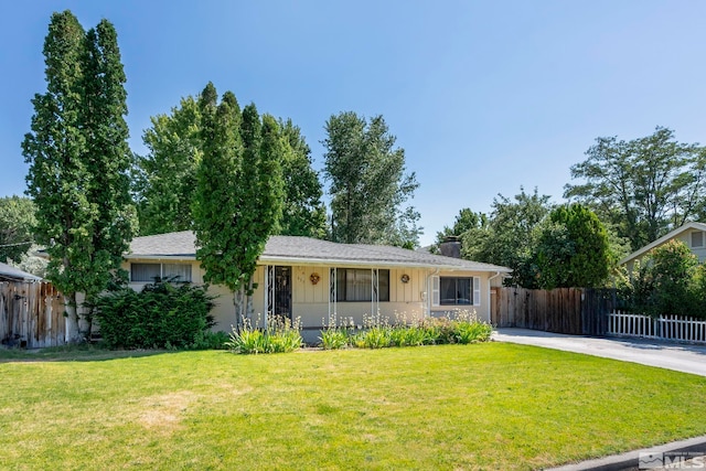 ranch-style house with driveway, fence, a chimney, and a front lawn