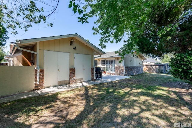 back of property with a chimney, fence, a patio, and a yard