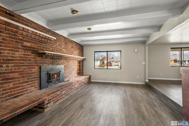 unfurnished living room featuring wood finished floors, beam ceiling, and baseboards