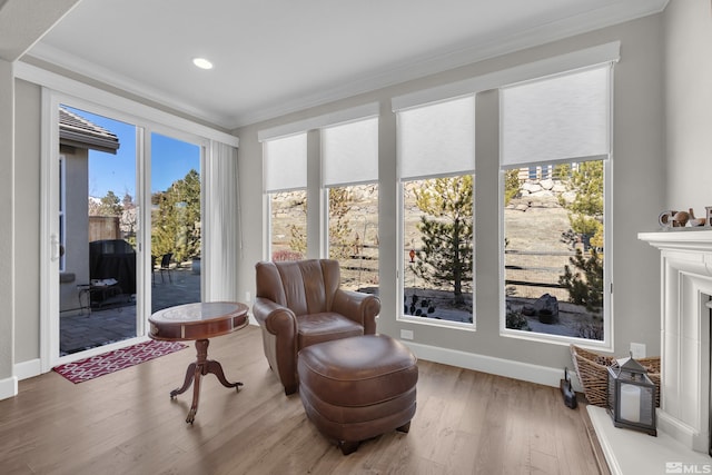 sitting room with a fireplace, crown molding, baseboards, and wood finished floors